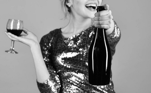 女士拿着赤霞珠或梅洛微笑的脸。瓶红酒在选择性聚焦。Winetasting 理念