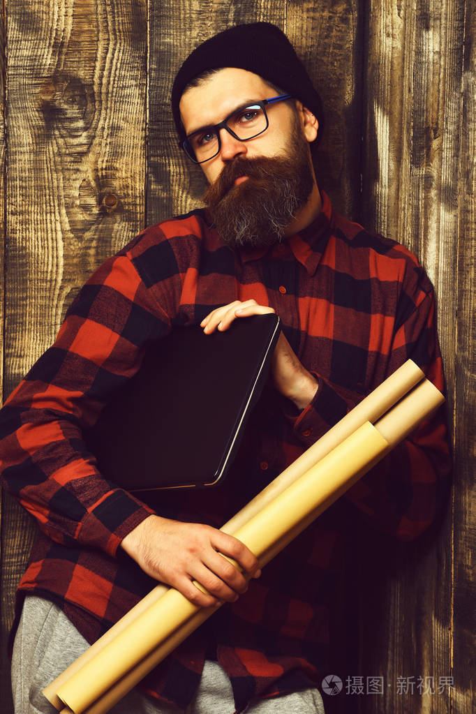 眼镜棕色老式木制工作室背景胡子野蛮的白种时髦手持笔记本电脑和工艺