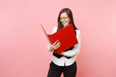 年轻的笑，快乐，成功的商业女人戴着眼镜，看着红色的文件夹，在粉红色的背景上隔离了文件。 女老板。 成就事业财富。 广告复制空间