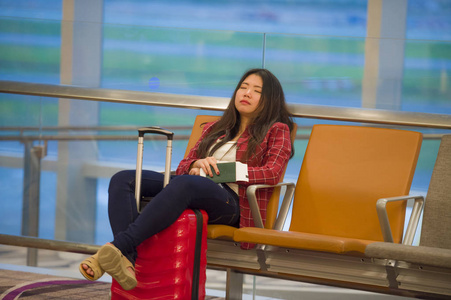 年轻疲惫疲惫的亚裔韩国女游客在机场睡觉，无聊地坐在登机口大厅等待航班延误或取消