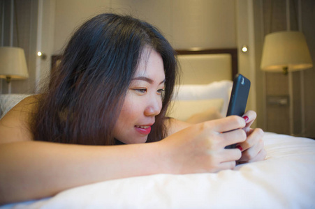 生活方式肖像年轻,快乐,漂亮的亚洲女性在家里,卧室或酒店房间躺在床