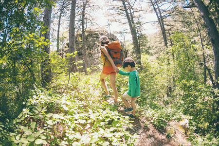 一个女人和她的孩子沿着森林小径散步。 一个带背包的男孩和他的母亲一起旅行。 和孩子们一起远足。 那孩子穿过松林。 活跃的暑假。 
