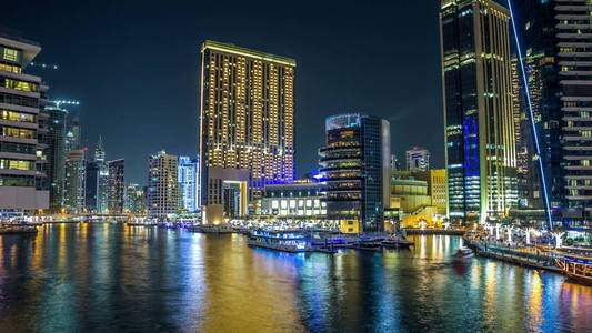 迪拜码头的Vew长廊与游艇和现代塔楼与餐厅从迪拜的桥梁夜间时间推移超移阿拉伯联合酋长国。 迪拜码头是迪拜的一个地区，也是一个人工