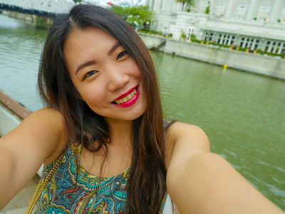 年轻美丽快乐的亚洲旅游女性的生活方式肖像，用手机自拍照片，微笑愉快快乐独自享受甜蜜的假期旅行
