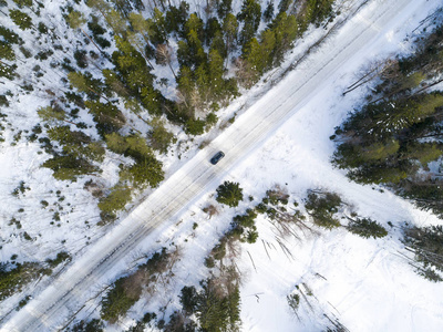 冬季道路上汽车的鸟瞰图。 冬季景观乡村。 用汽车在路上对雪林进行空中摄影。 用无人机从上面捕获。 空中照片。 四翼飞机。 空中汽