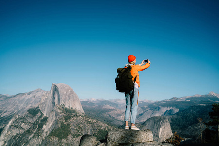 风景图片手机年轻女性的后景使用智能手机在山顶拍摄冒险女旅行博主的