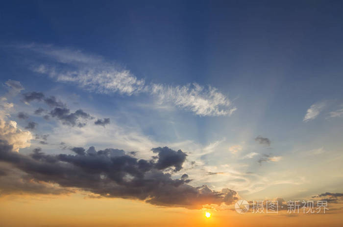 在晴朗的天空上,由明亮的橙色黄色太阳照亮的深蓝色云彩的美丽景色.