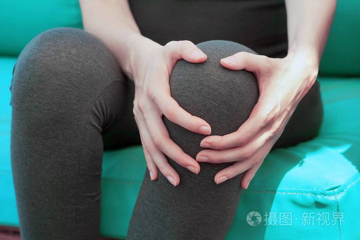 膝盖疼用痛苦的膝盖关闭女性腿年轻女子感到关节疼痛有健康问题用手摸
