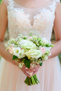 美丽的婚礼花束新鲜的白色和粉红色玫瑰在新娘手中的户外自由空间。 新娘花束靠近