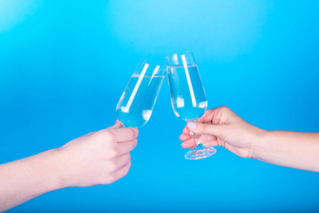 男人和女人在蓝色背景上敲打着带香槟的酒杯. 干杯.