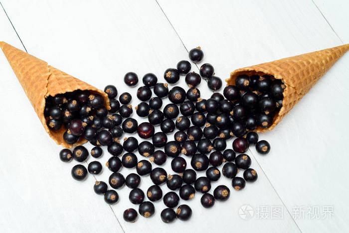 甜的新鲜有机黑加仑在华夫饼锥的顶部视图新鲜浆果在白色木制背景和