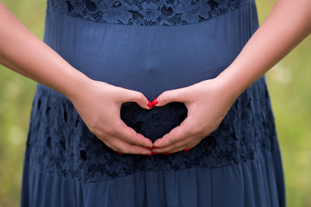 s hands make heart  symbol on belly on green background. Hands i