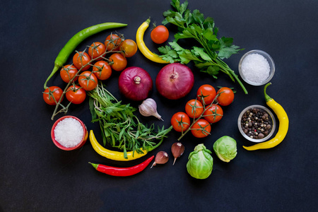 五颜六色的香料在勺子和西红柿在黑暗的复古背景。顶部视图。食品和烹饪配料。素食或饮食的概念。带有可用文本空间的背景布局