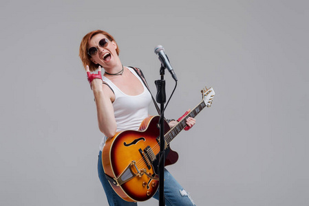 电动晾衣架一位年轻的女音乐家的肖像,手里拿着一把电吉他,灰色背景上
