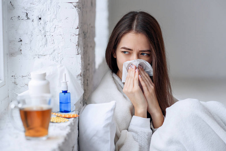 感冒和流感。 生病的女人感冒，感觉生病，打喷嚏在纸擦。 特写美丽的不健康女孩被毯子覆盖擦拭鼻子。 医疗保健概念。