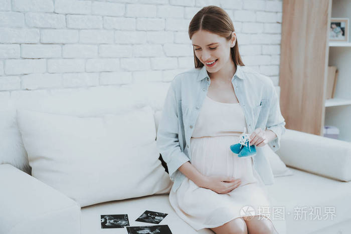 孕妇为新生儿拿鞋快乐的母亲观念健康的怀孕观念年轻的