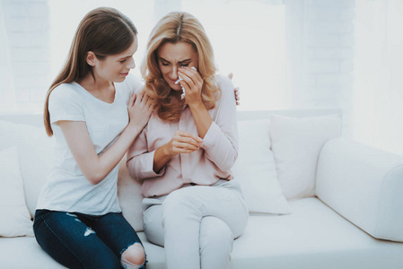 女人在家安慰不幸的十几岁的女儿。 坐在家里的沙发上。 有问题的女孩。 家庭冲突。 父母和孩子。 不开心的女孩。 交流概念。 关系