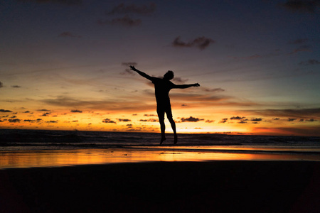 日落时在海边的人. 人在夕阳的背景下跳跃.照片
