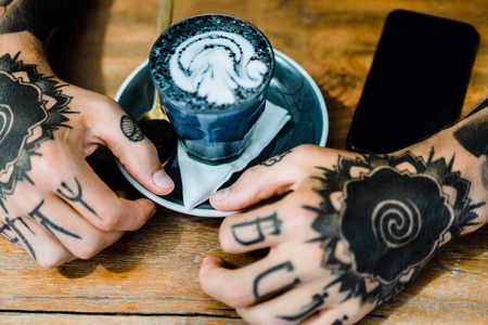 纹身的手。 手拿着一杯咖啡。