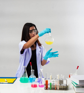 实验室里使用试剂的试管做防护眼镜的化学家，在触摸试管时，她戴着蓝色橡胶手套保护手，周围光线模糊。