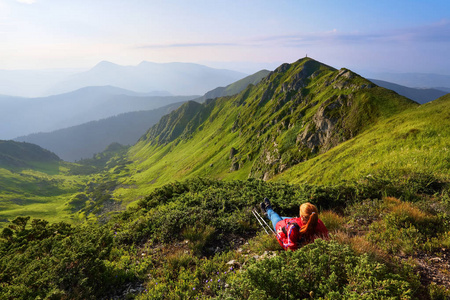 与高山的景观..天空有云。森林之路。女孩正在铺花的草坪上。生态旅游。有趣的夏日。