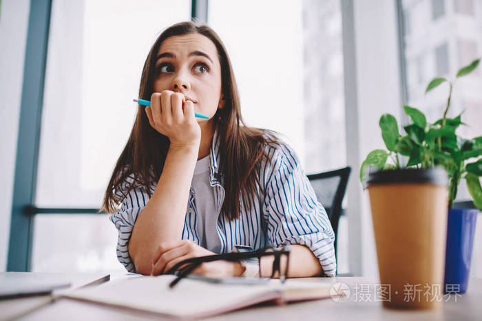 聪明的年轻女学生,带着笔思考做作业,思考解决问题,创造性的白种人,坐