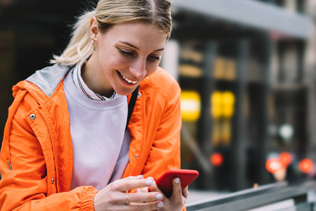 关闭年轻女性使用手机数据互联网连接，同时站在城市街道。 快乐微笑的白种人时髦女孩通过智能手机上的聊天应用程序阅读短信