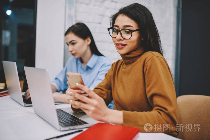 在校园里做作业时,hipster女孩通过手机与朋友在社交网络上聊天,女