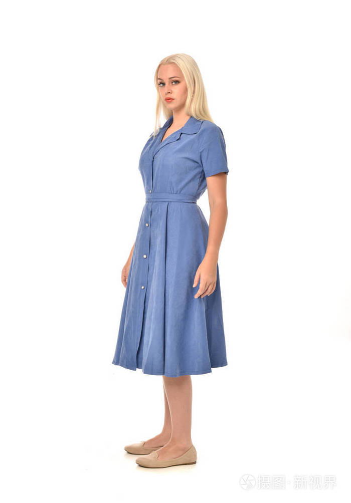 穿蓝色连衣裙的金发女孩的全长肖像. 站姿. 孤立在白色工作室背景上.