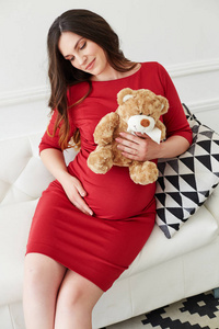 怀孕的美女年轻的母亲肖像抚摸她的腹部和微笑.