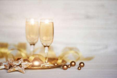 圣诞假期背景。 庆祝主题。 两杯香槟，金色丝带和圣诞节装饰在模糊的白色背景上。 庆祝概念免费空间的文本。