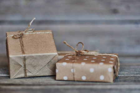 木桌上的工艺纸生态纸上的盒子。 包裹或礼物用绳子系在一起。 棕色纸包裹礼品盒与绳弓在一个古老的乡村木材背景。 你设计的背景。