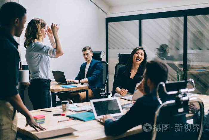 多元文化的男女办公室职员穿着正式服装,在财务公司的工作场所坐着玩.