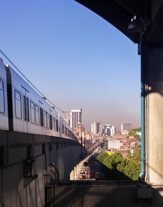 麦德林地铁列车哥伦比亚从医院站，以查看市中心与蓝天和厚厚的空气污染。 高架地铁电气系统铁路和城市天际线的结构细节。