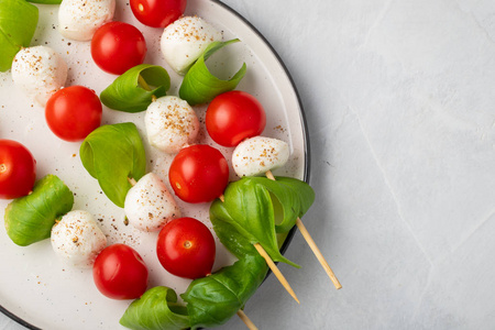 Caprese 沙拉串与西红柿, 意大利干酪和罗勒, 意式食品和健康的素食饮食概念在一个光的背景。具有复制空间的顶部视图。平躺