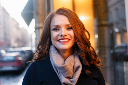 热情微笑的女孩,在阳光下在城市里摆着闪亮的卷发.