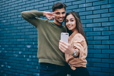 一对快乐的时髦情侣在智能手机摄像头上合影留念,男女青少年穿着休闲