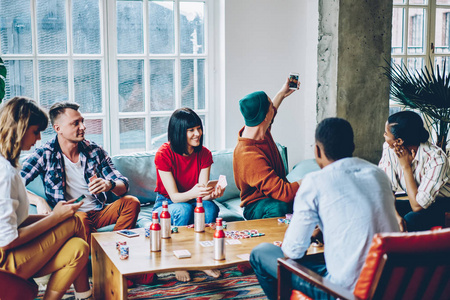 积极的多元文化朋友,玩棋盘游戏和在一起的时间在现代公寓.