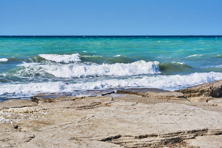 美丽的海景，有嘈杂的泡沫波和岩石海岸。 朝绿松石的海洋看。 涨潮时的海浪。 带泡沫的海边波浪。 暑假。 旅行概念。