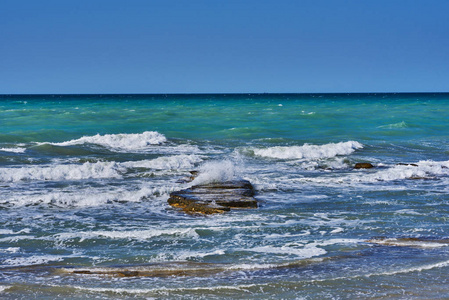 美丽的海景，有嘈杂的泡沫波和岩石海岸。 朝绿松石的海洋看。 涨潮时的海浪。 带泡沫的海边波浪。 暑假。 旅行概念。