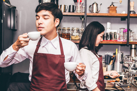 一对小企业主的肖像，微笑着，在咖啡馆的柜台后面工作。情侣咖啡师用咖啡机在咖啡馆里煮咖啡