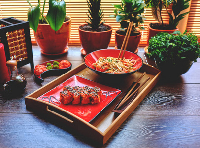 桌子上有一个木制的调料，上面有两个红色的盘子，上面有日本和虾和虾