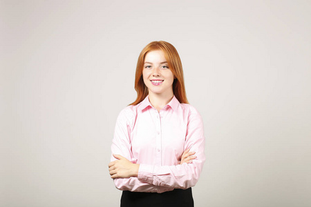  pink blouse standing with arms folded on chest. Attractive woma