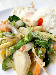 将蔬菜与肉汁酱和泰国式煎蛋混合在白色背景的白色盘子中。 素食健康食品。