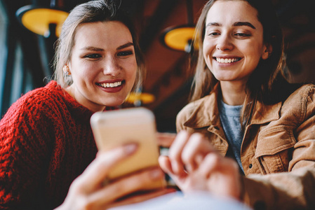 两位微笑的女性博客作者利用手机上的照片应用创建了一个出版物，快乐的千禧女性通过现代手机与朋友聊天，享受休闲技术