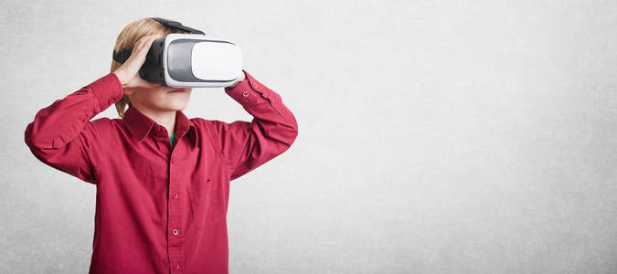 水平拍摄的小男孩戴着VR眼镜，看到虚拟现实孤立在白色背景上，有广告内容的复制空间。 虚拟耳机眼镜里的男孩子。 今后的进展