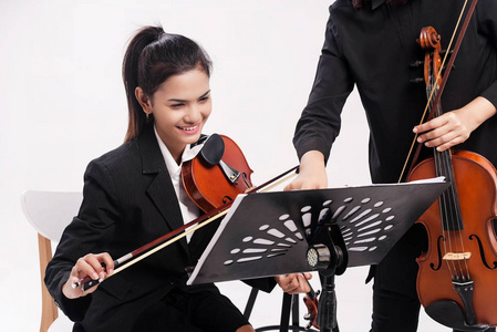 音乐学校课这位穿着黑色制服的美女正在老师那里学小提琴,他正在看着