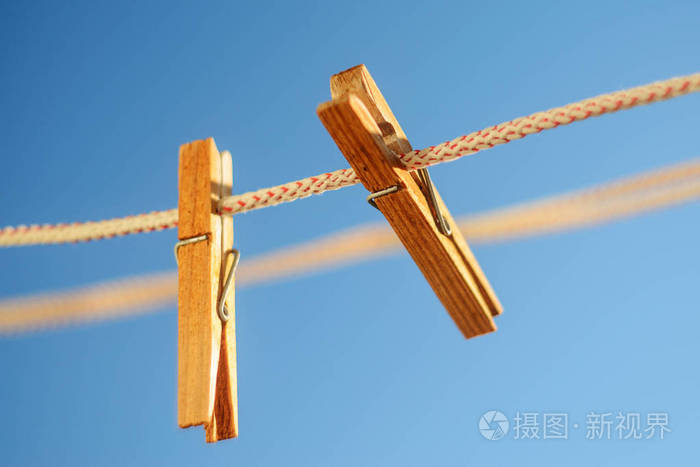 在蓝天背景下的晾衣绳上有两个木制的衣夹