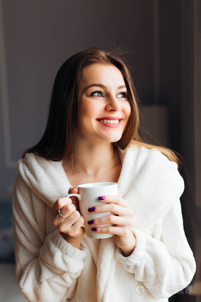 特写一个可爱的年轻女人享受热茶的肖像. 女人拿着一杯茶或咖啡.