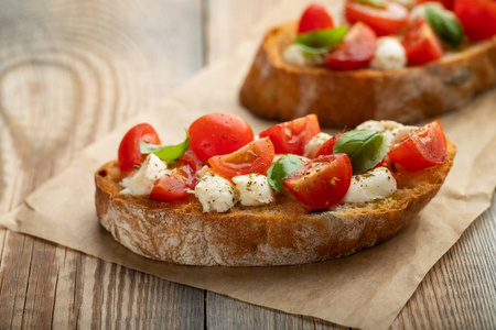 在一张古老的乡村桌子上放着西红柿马扎雷拉奶酪和罗勒。 传统意大利开胃菜或小吃反胃。 有复制空间。
